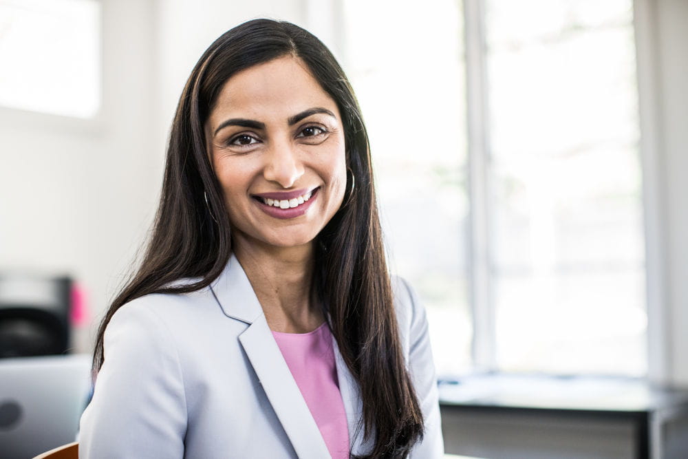 A professional portrait of an individual smiling in a work setting.